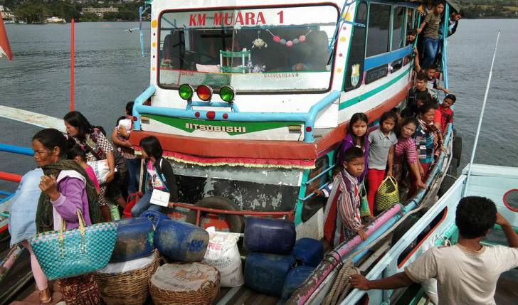 kapal motor penuh muatan penumpang di danau toba pelabuhan balige